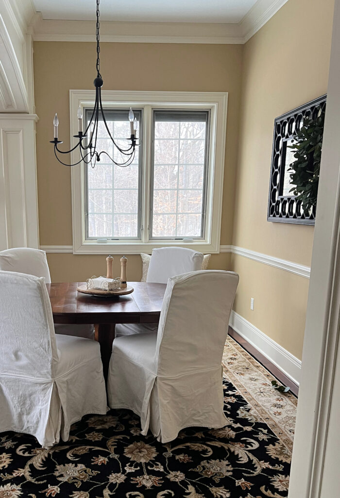 Benjamin Moore Wilmington Tan and Sherwin Williams Antique White trim, formal dining room, slipcovered chairs, red oak wood flooring, area rug, crown molding