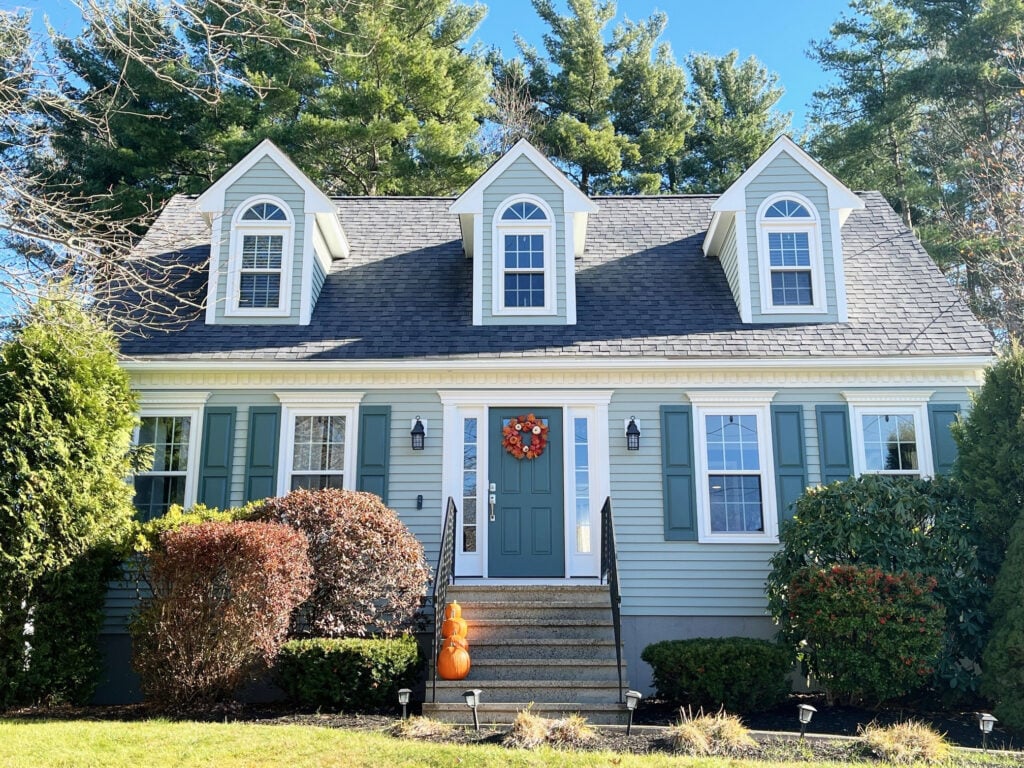 Exterior cape cod beachy style home with blue-green-gray siding paint color, Sherwin Oyster BAy, Pure White trim, gray fiberglass roof, Rocky River teal shutters and front door,