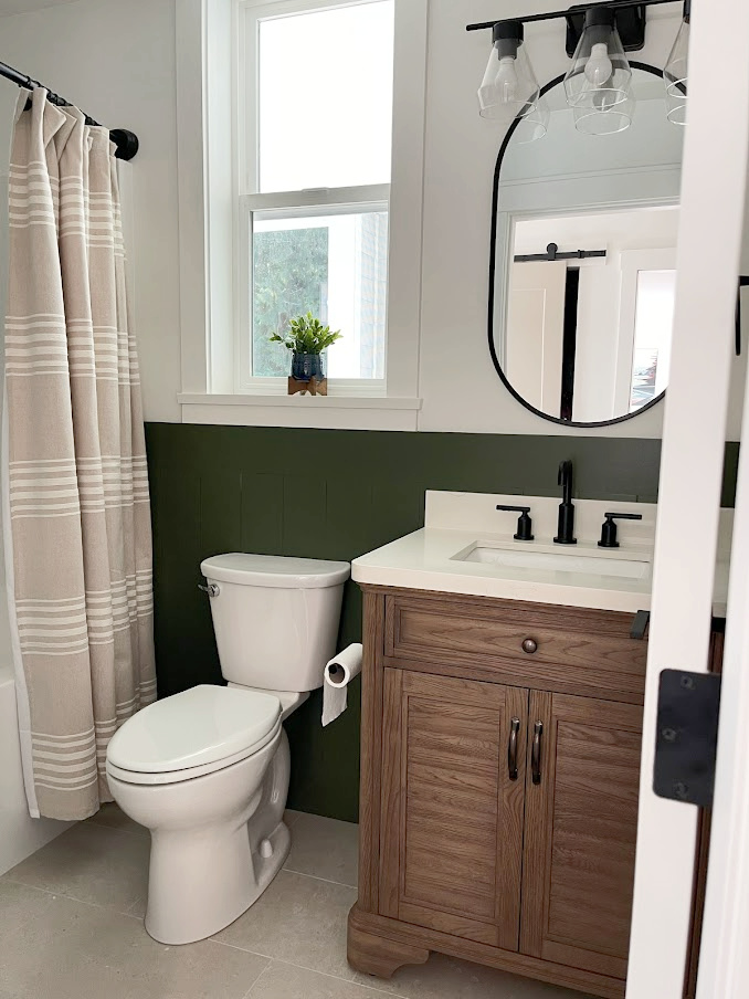 small bathroom, Sherwin Williams Ripe Olive green shiplap, Benjamin Moore White Dove, curved shower rod, beige tile, wood vanity, marble top. Kylie M