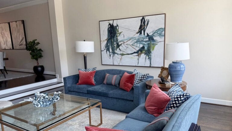 Livingroom walls painted Sherwin Williams Natural Tan. Blue sofas with red accents and artwork