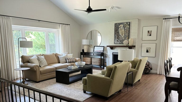 Sherwin Williams White Duck in a split-level, 1970s living room on a painted brick fireplace and walls, oak floor and green accent chairs with beige sofa