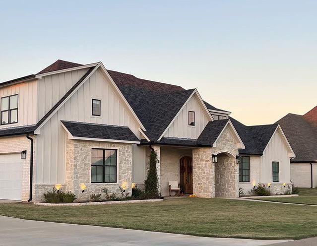 Sherwin Williams warm off-white taupe paint color on exterior siding with cream, beige, taupe stone, black fiberglass roof, black windows