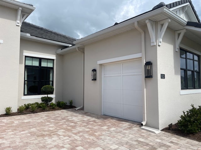light tan warm beige paint color on exterior with Sherwin Williams Pure White trim, orange, pink, gray stone driveway, black windows