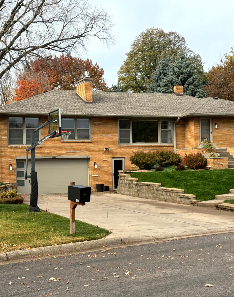 exterior orange stone and brick, weathered wood fiberglass roof, sherwin williams taupe tone on the garage door, windows, anad trim.  