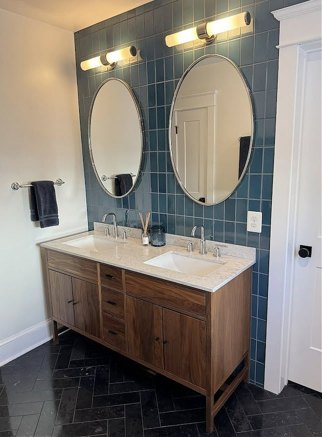 small bathroom, black herringbone marble look tile floor, dark wood vanity, marble look countertop, blue accent tile on wall behind vanity
