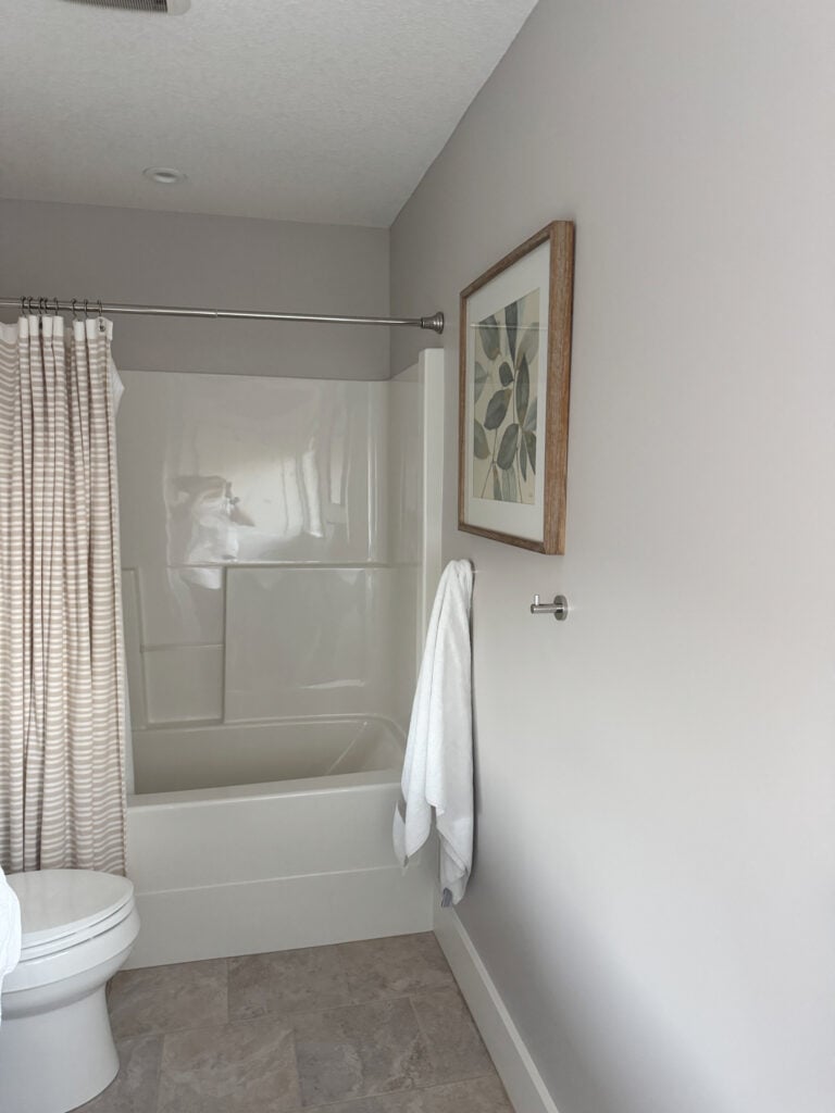 2000 bathroom update with off-white shower surround, beige tile floor and Sherwin Williams Pediment on walls