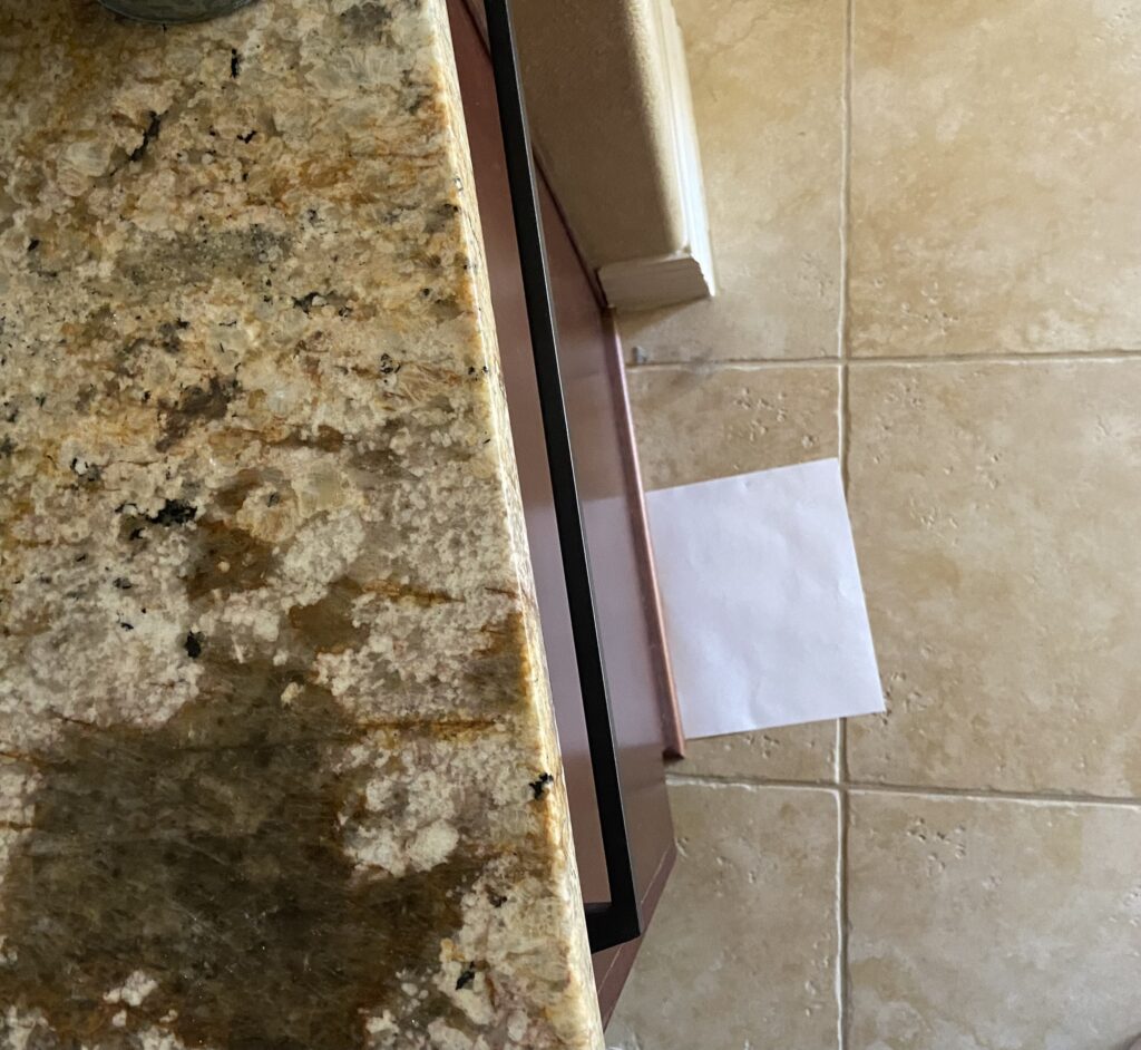 Sienna Typhoon Bordeaux granite countertop, gold, taupe, with beige tile floor and cherry cabinets (1)