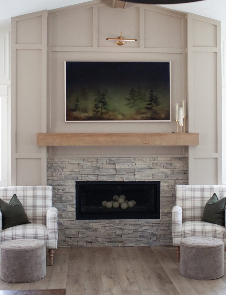 Ideas to update a room with 1990s 2000s fireplace, stacked stone, wood mantel, moldings, trim panels painted Sherwin Williams Balanced Beige, accent chairs, graywash LVP wood look floor