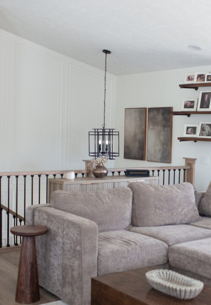 Staircase in split level home from living room view, black spindles, wood hand railing, Sherwin Williams Cold Foam warm white walls, taupe greige sofa