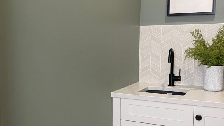 Sherwin Williams Dried Thyme green paint color on walls with white cabinet and black faucet