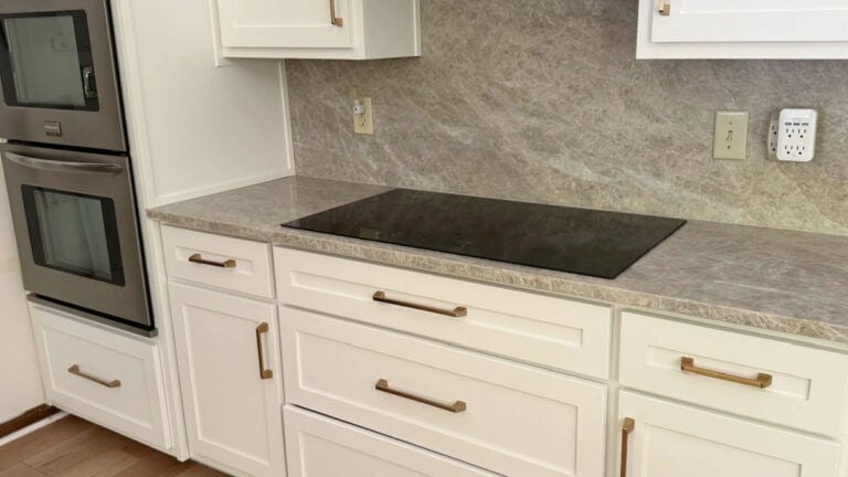 Taj Mahal quartzite countertop and slab backsplash with warm white cabinet paint color and gold hardware