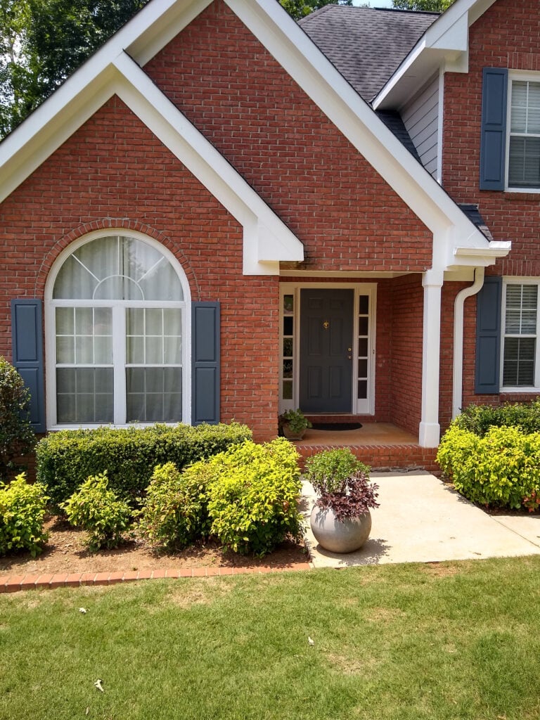 South-facing, Red brick exterior with blue shutters, Sherwin Williams Gibraltar, Pure White trim