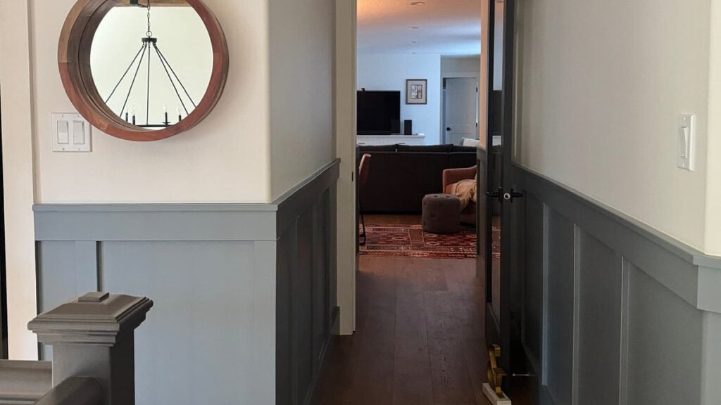 Hallway with board and batten painted Sherwin Williams Foggy Day. Upper walls Benjamin Moore White Dove. Dark hallway