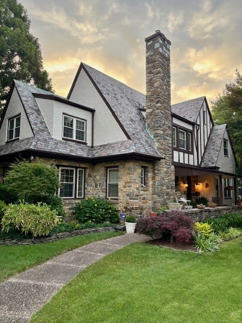 Tudor style exterior with stone fireplace, asphalt roof, dark brown trim, off-white windows, painted Sherwin Williams Accessible Beige