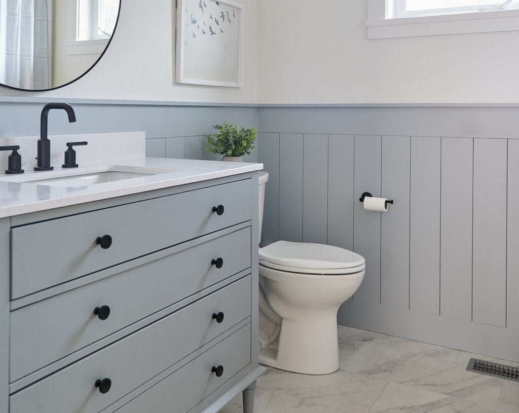 Sherwin Williams Network Gray painted lower wall vertical shiplap, gray vanity, marble look porcelain tile floor in bathroom, White Dove upper walls