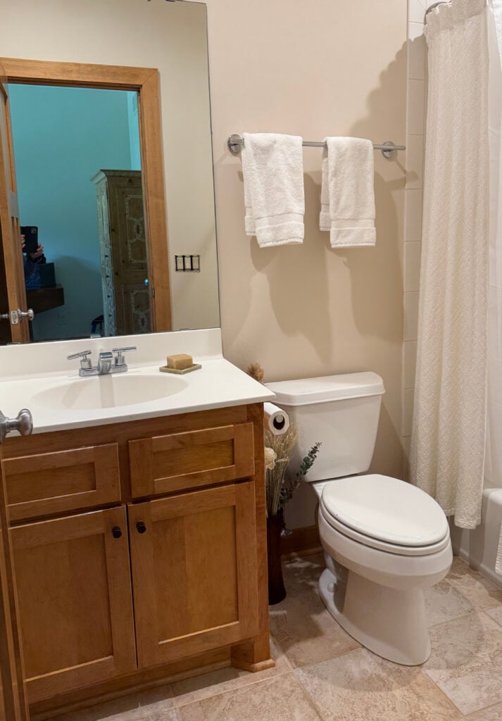 Sherwin Williams Divine White with beige tile floor, red stained cherry wood cabinet in small bathroom, white countertop