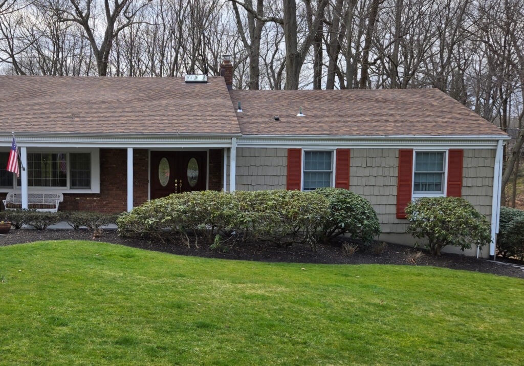 BEnjamin MOore Creekside Green on exterior siding of ranch style home with brown asphalt roof Hickory Timberline, orange-red shutters and brick.