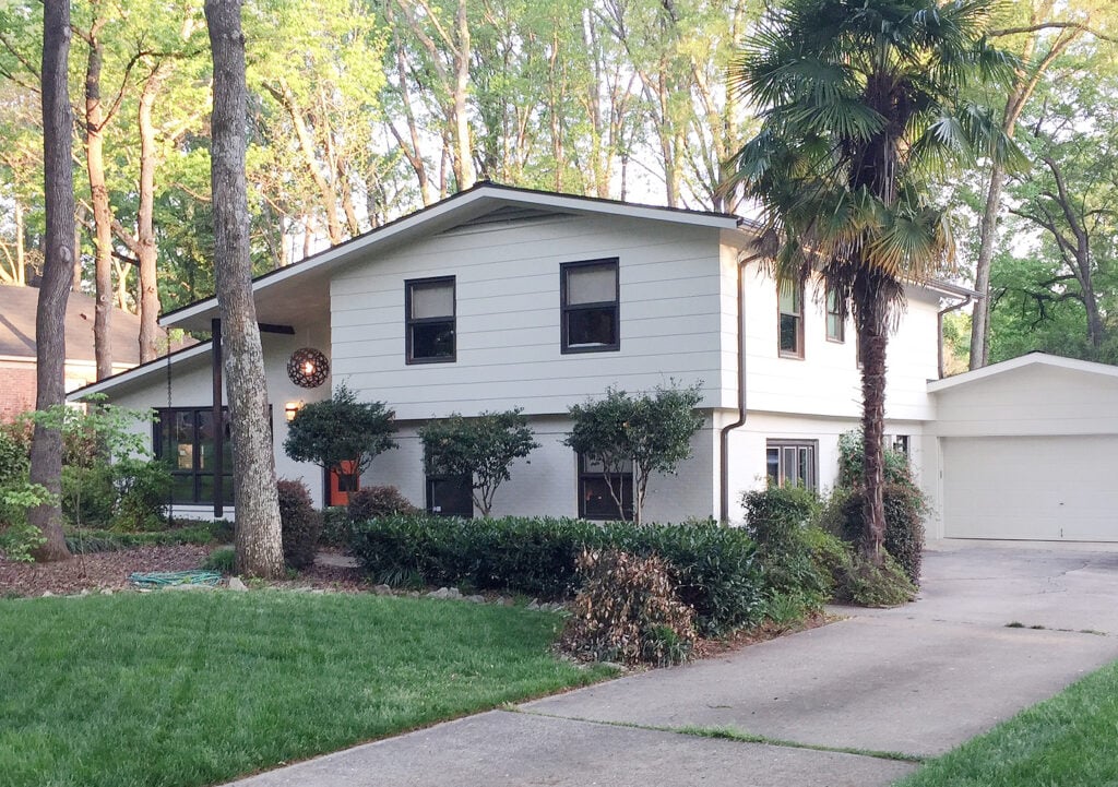 Benjamin Moore Ballet White with Willow, dark brown trim. Mid-century 1970s split level exterior of home, creamy warm off-white paint color