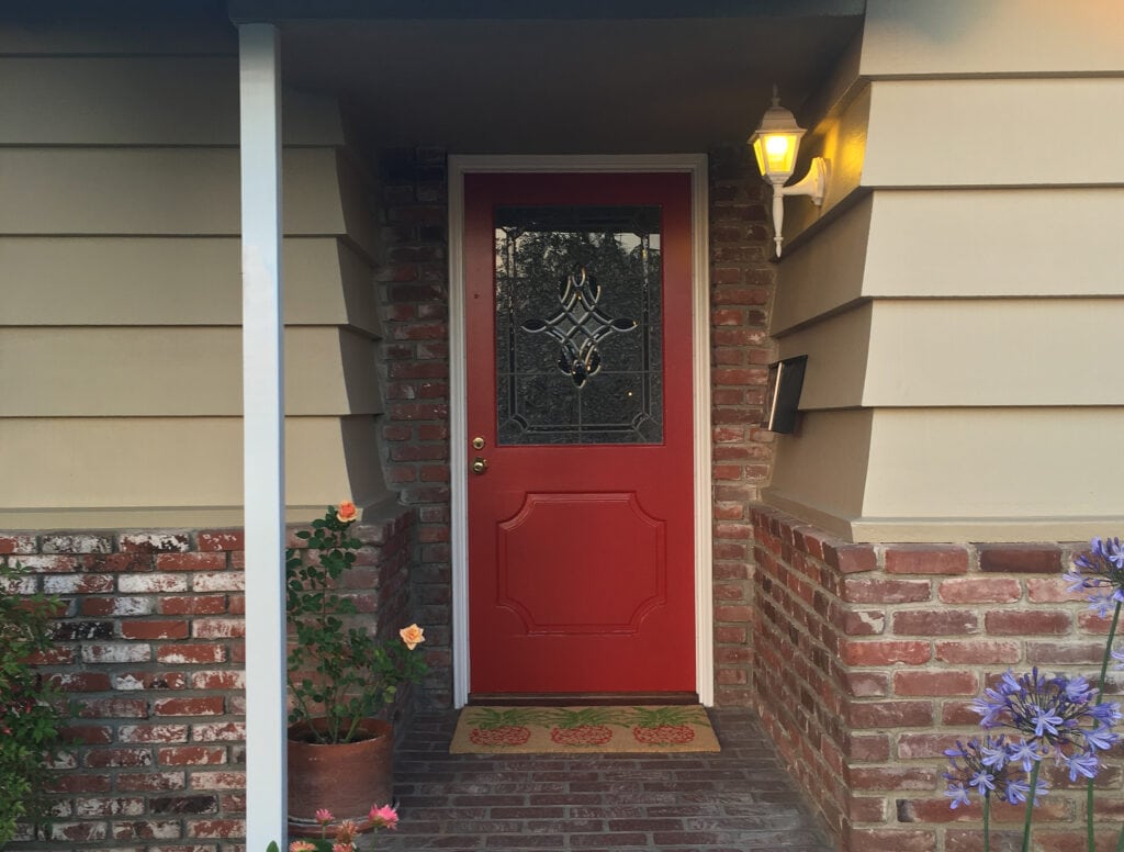 Benjamin Moore Greenbrier Beige exterior siding on cottage style home with red brick and Chinese Red front door, white trim