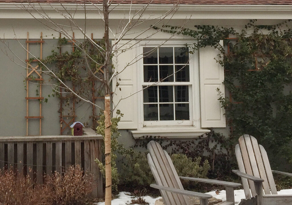Benjamin moore Rockport Gray exterior painted stuccc on home with cream shutters and trim painted Sail Cloth