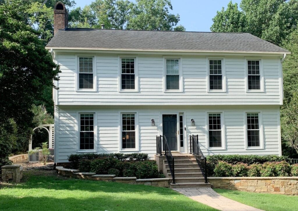 Colonial style exterior with Sherwin Williams Pure White, white windows, Benjamin Moore Gray 2121-10 front door, orange stone