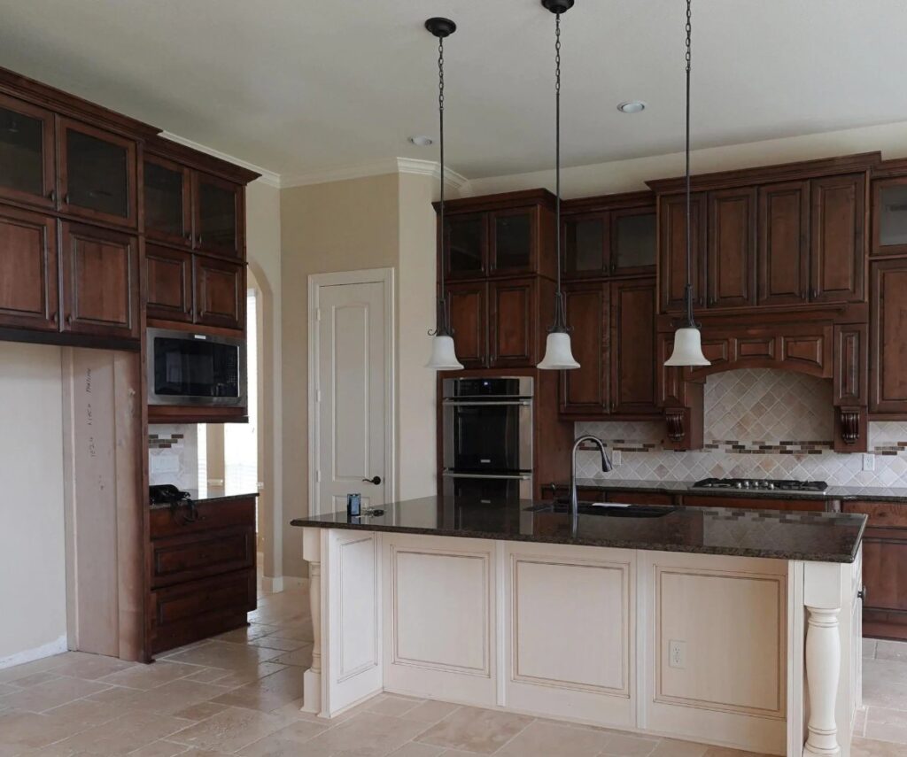 Dark wood kitchen cabinets, tuscan or mediterranean style kitchen, 2000s home, travertine tile floor and backsplash, warm white ceiling, dark black granite counters