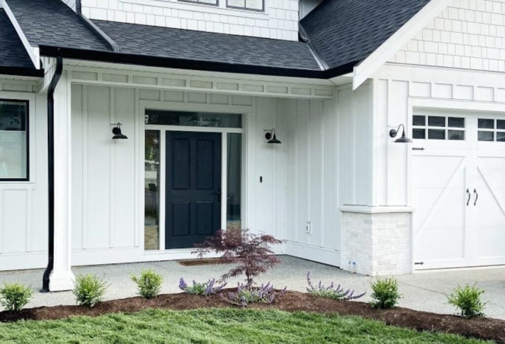 Exterior Arctic White, James Hardie board batten siding, dark gray black roof, black gutters, white garage door same color as trim. Tricorn Black front door, whitewash brick, modern farmhouse style