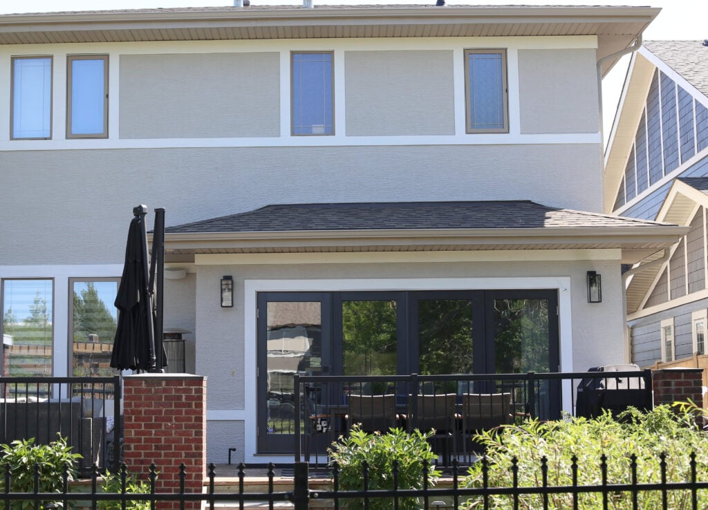 Exterior of back of home painted Sherwin Williams Agreeable Gray, Pure White trim, Benjamin Moore Wrought Iron on back doors