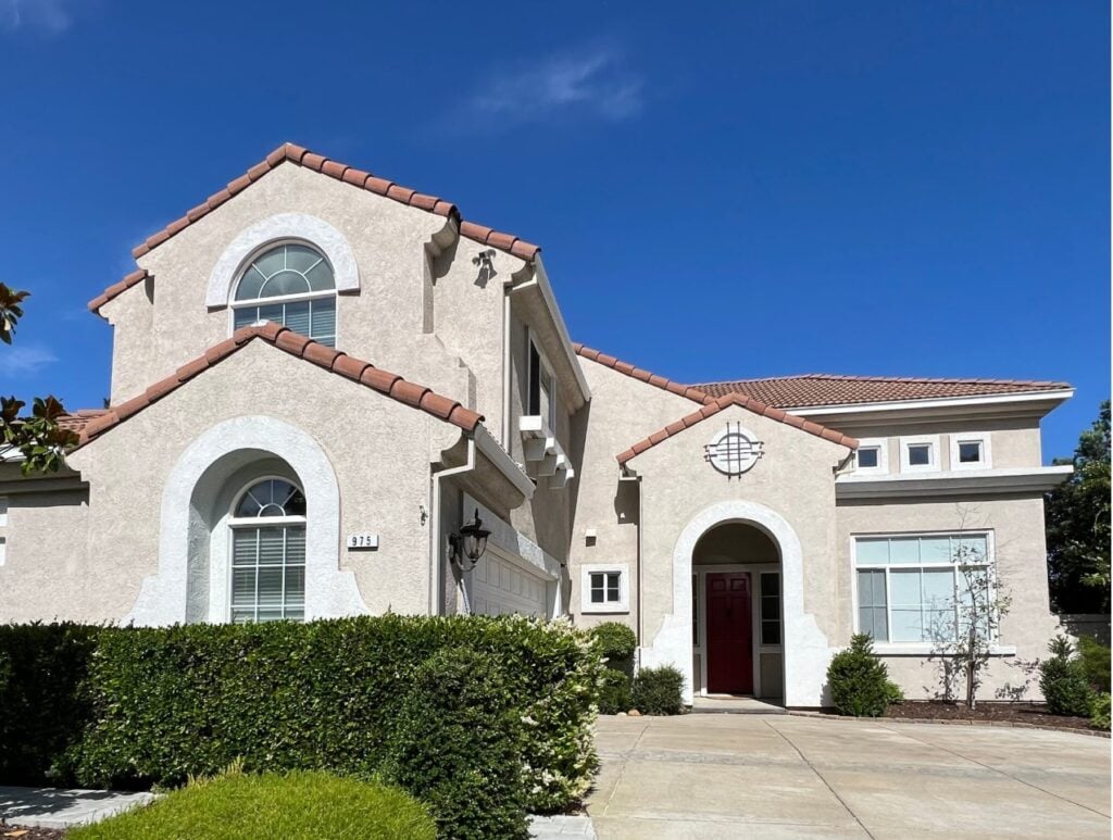 Exterior stucco, mediterranean style home with red tile (terracotta) orange roof, flexible off-white beige paint color, stucco trims, white windows