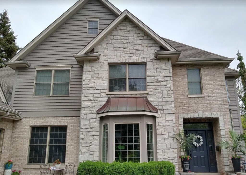 Exterior with brick and paintable siding, Benjamin Moore smokey taupe, metropolis wrought iron, taupe windows, matching gutters, taupe roof, metal roof in copper