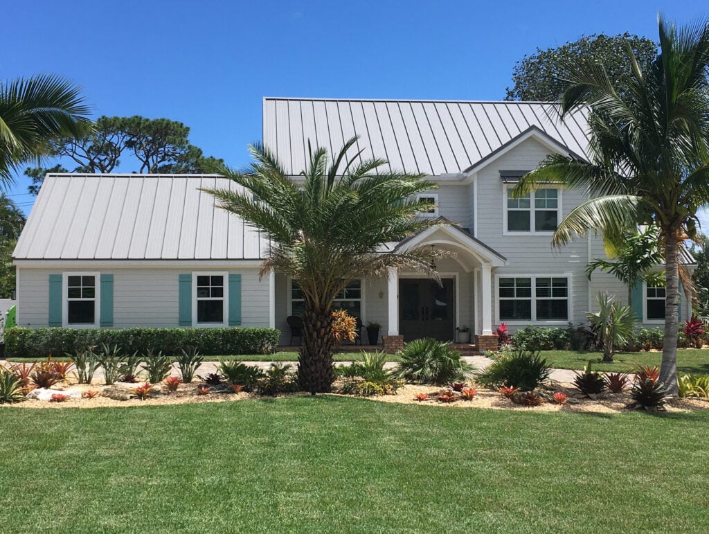 Florida style home with gray metal roof, white trim, Benjamin Moore Gray siding color, teal blue green shutters, white windows and gutters