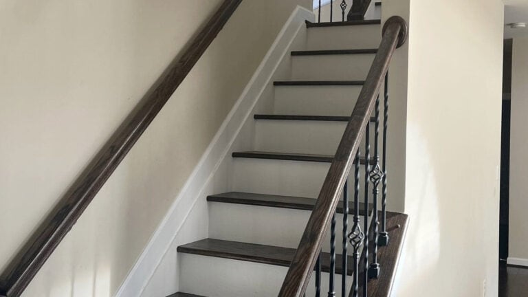 How to update a 2000 staircase, Manchester tan walls, dark wood steps, painted white riser, and wood hand railing with iron spindles