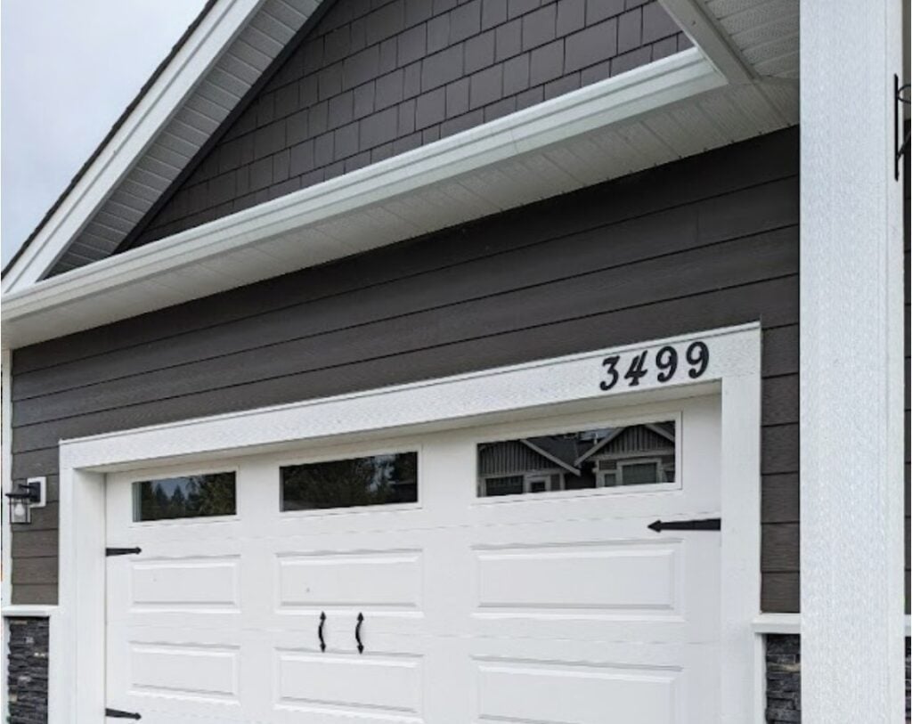 James Hardie Rich Espresso dark brown exterior siding on house with Benjamin Moore Cloud White trim and dark black stone, white garage door, black hardware and windows. White soffits match trim