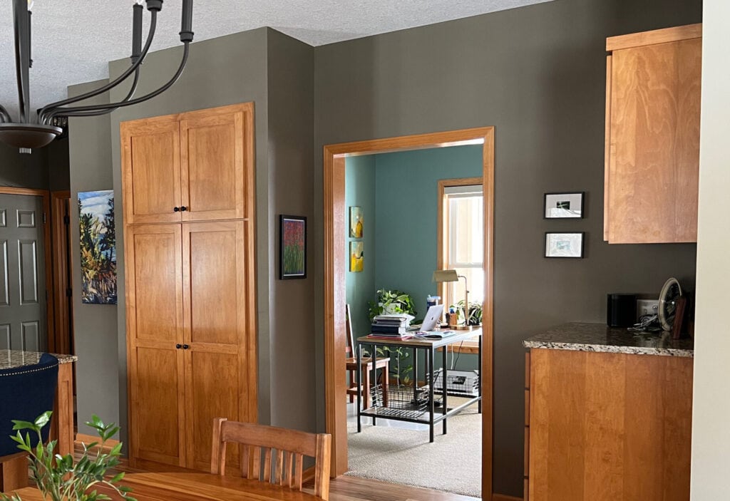 Kitchen and eating area with orange stained wood trims, doors, cabinets, looking into a home office in blue-green