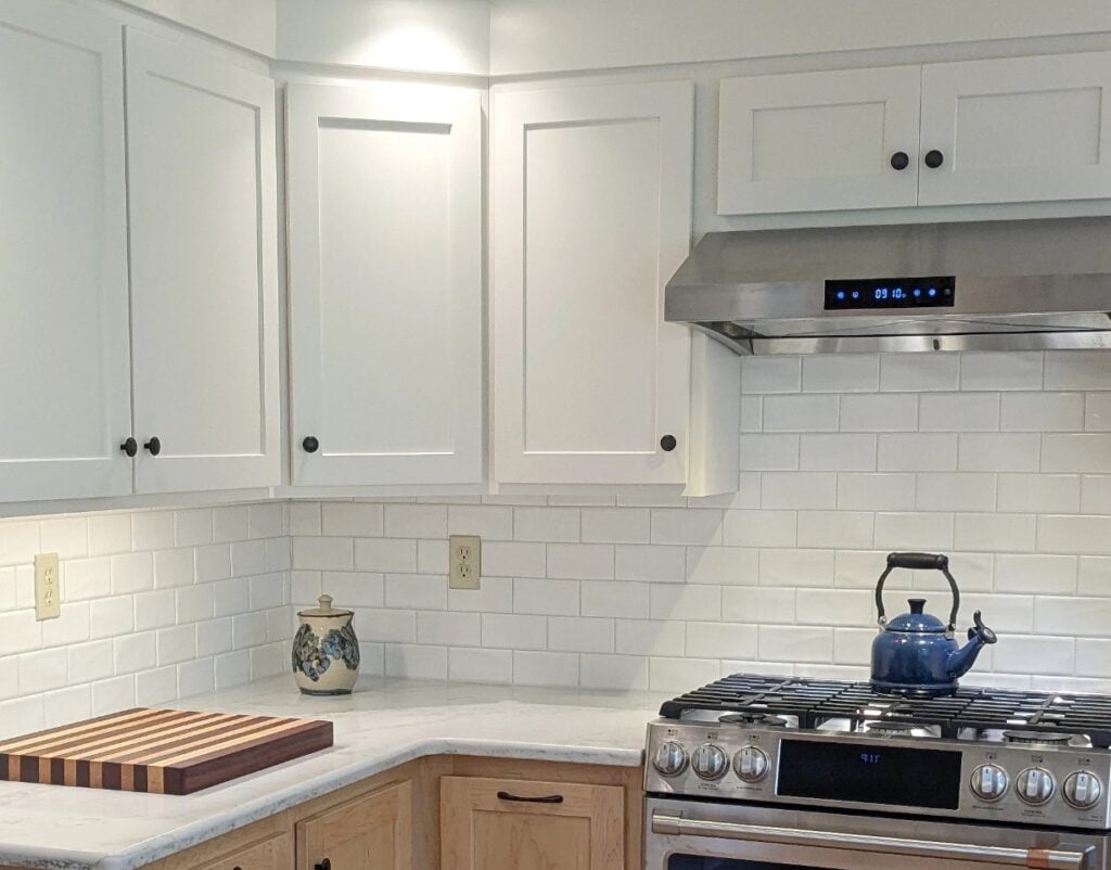 Sherwin Williams Alabaster kitchen cabinets, white quartz countertop, subway tile backsplash, natural birch light wood lower cabinets, black hardware, stainless timeless white cabinets