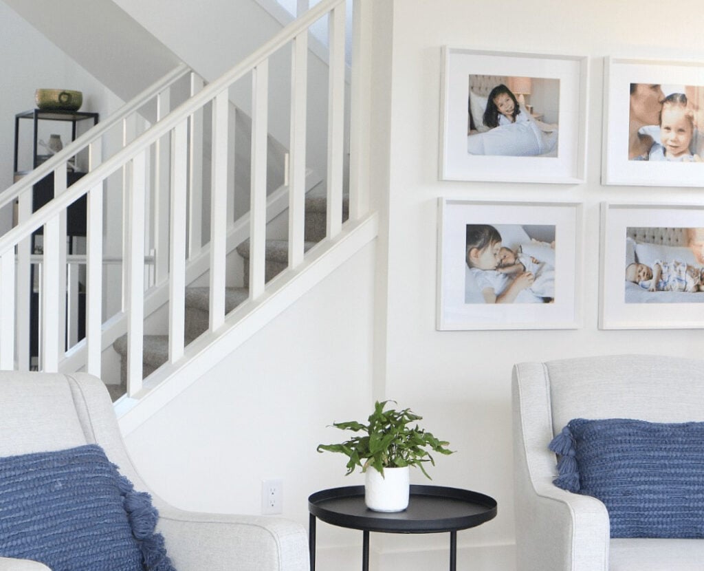 Sherwin Williams Pure White walls, trims, stair railing, light gray accent chairs, blue toss cushions, gallery wall, south-facing light