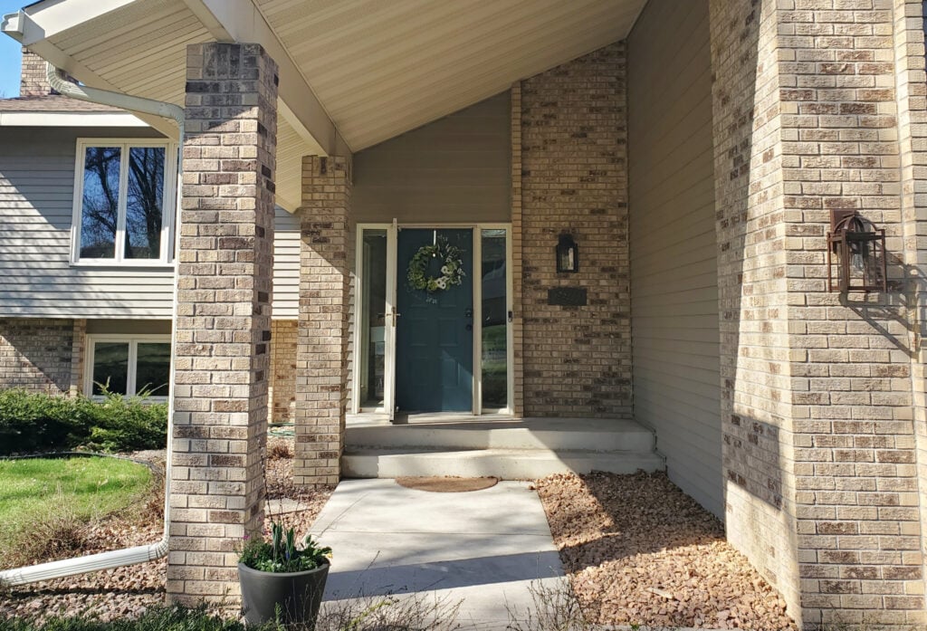 Sherwin Williams Still Water teal painted front door on 1970s exterior with brown or beige brick
