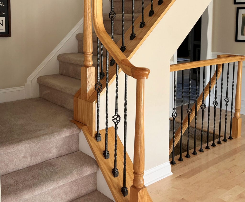 early 2000s taupe pink carpet on stairs, golden oak maple hand railing, cage style wrought iron metal spindles, outdated