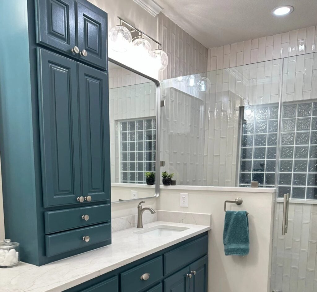Bathroom with painted wood (oak) vanity cabinet in Sherwin Williams Riverway (teal) with vertical subway tile in shower, quartz countertop, soft gray