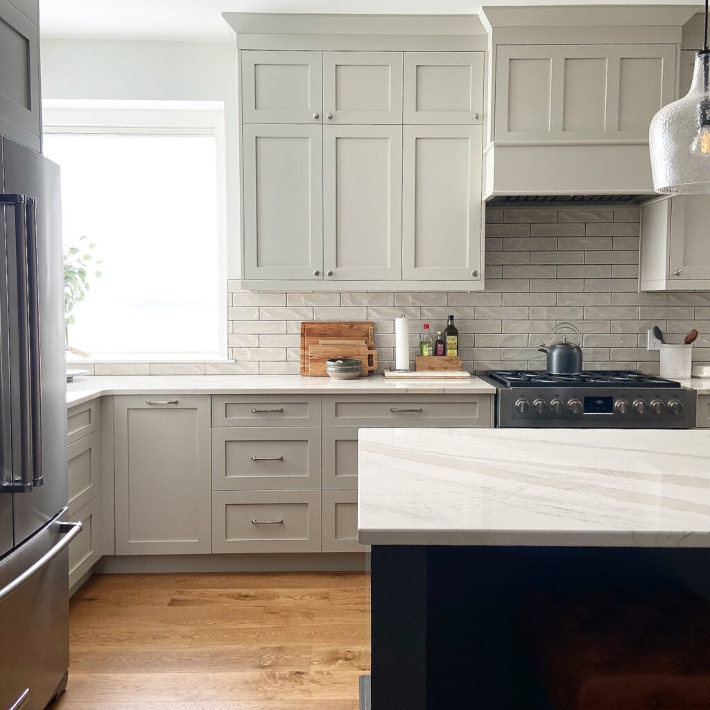 Benjamin MOore Revere Pewter darkened, similar to Sherwin Williams Mindful Gray, warm, off-white quartz countertop, gray subway tile backsplash, White Dove trim and walls