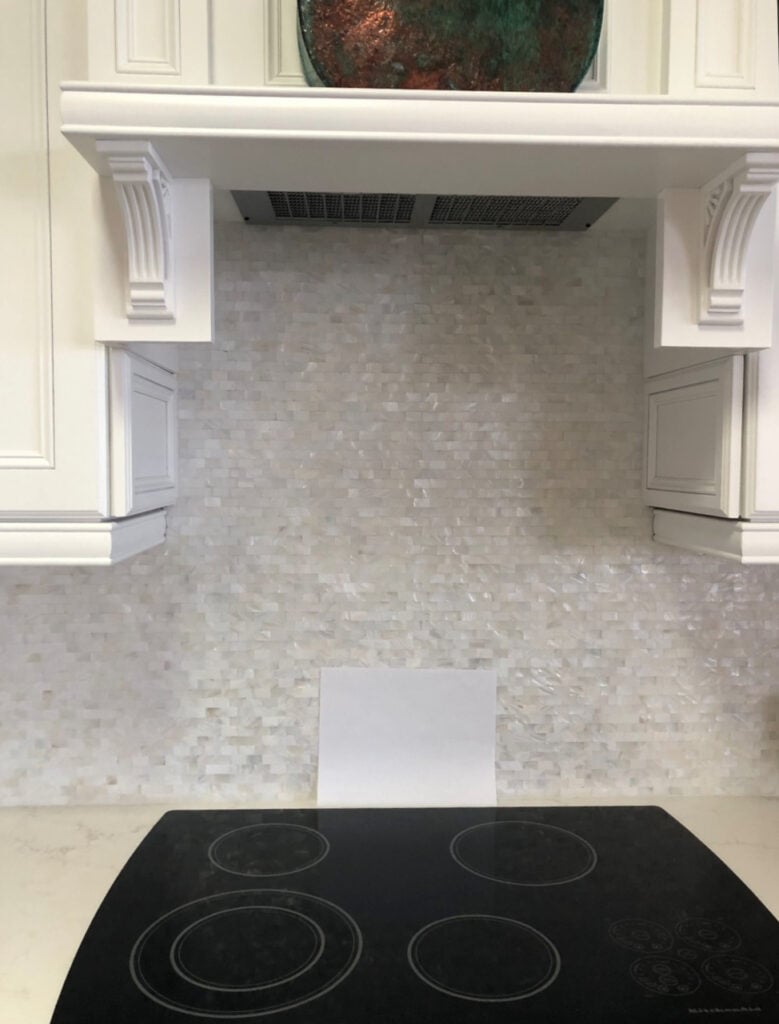 White cabinets cabinets with mother of pearl backsplash tile mosaic, white quartz countertop in kitchen