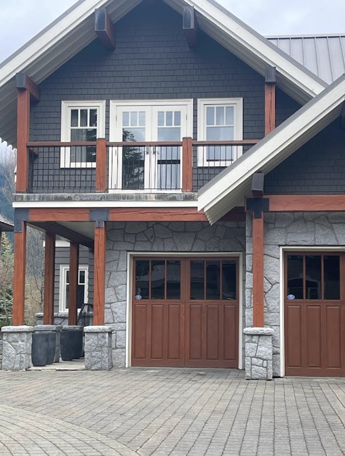Exterior with gray natural stone, cherry red stained wood garage doors, beams, and some trims, white trims and gray siding