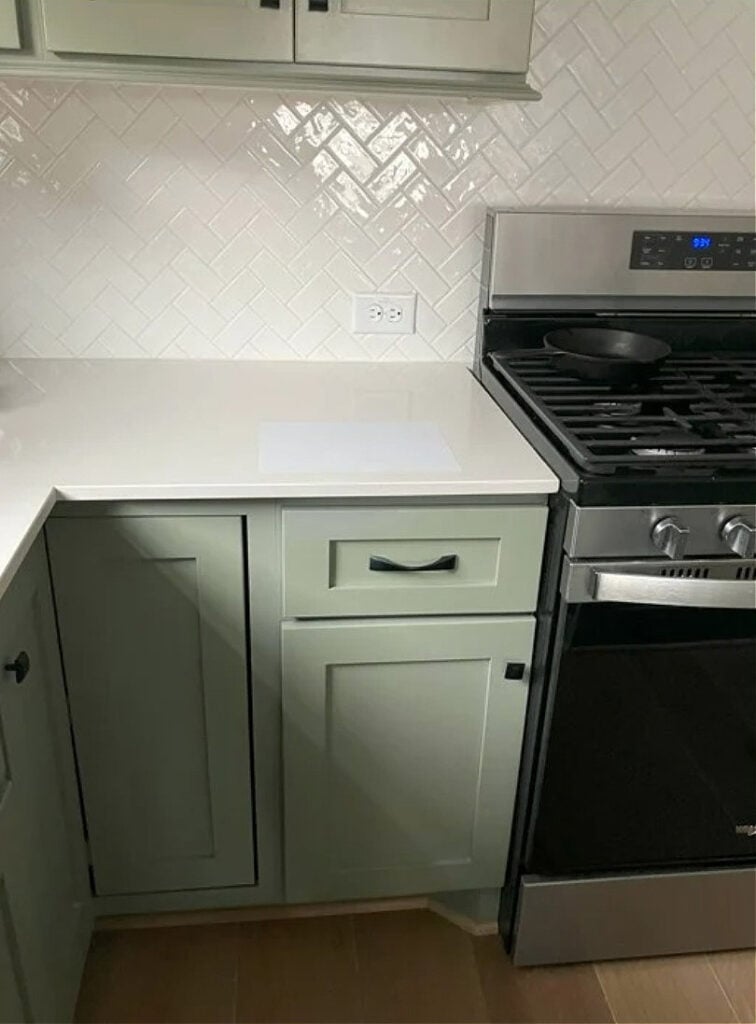 Green painted cabinets, Sherwin Williams Evergreen Fog with herringbone pattern white subway tile backsplash
