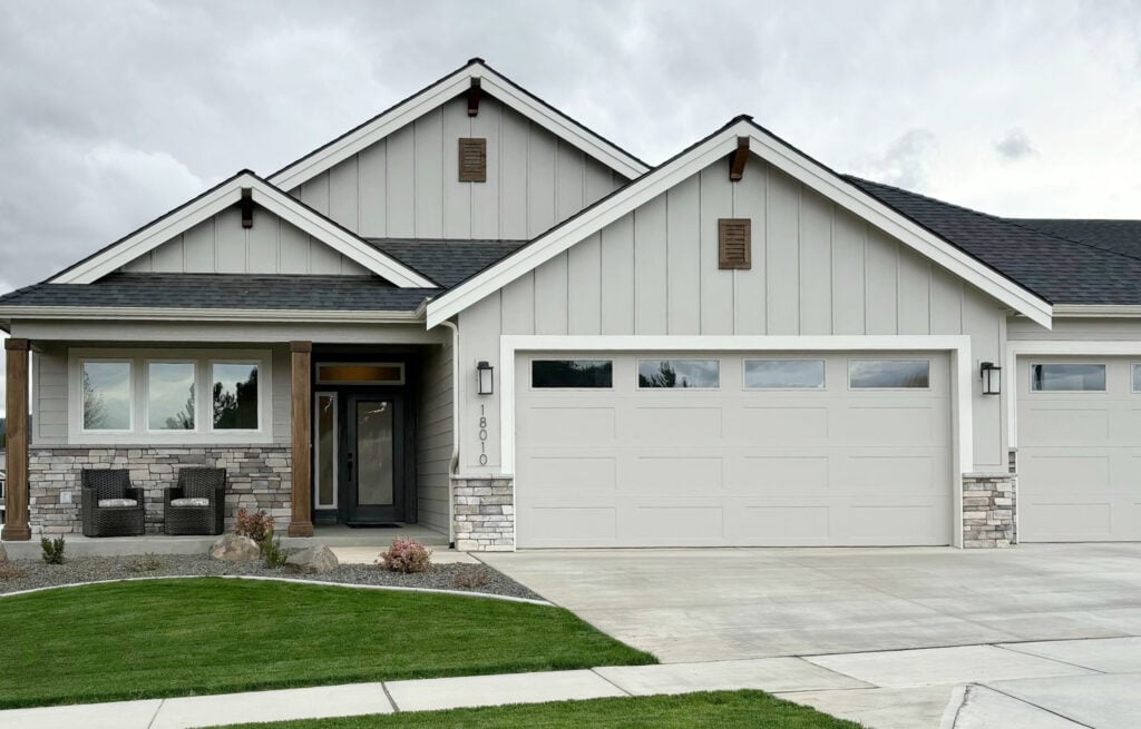 Sherwin Williams Agreeable Gray exterior with Pure White trim, gray, white, and beige stone and garage doors and gutters that match the house color