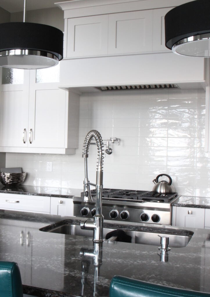 Sherwin Williams High Reflective White cabinets with white stacked subway tile. Black granite countertop