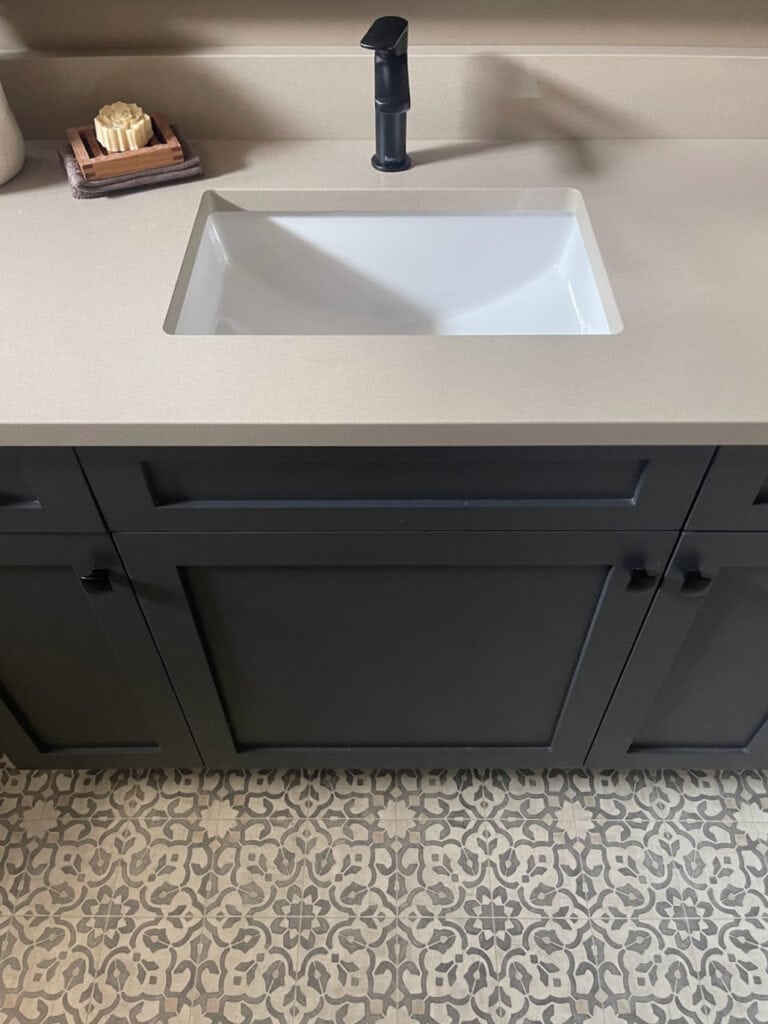 Sherwin Williams Iron Ore, dark, soft black bathroom vanity, linoleum or vinyl floor that looks like patterned tile in beiges, taupe quartz countertop