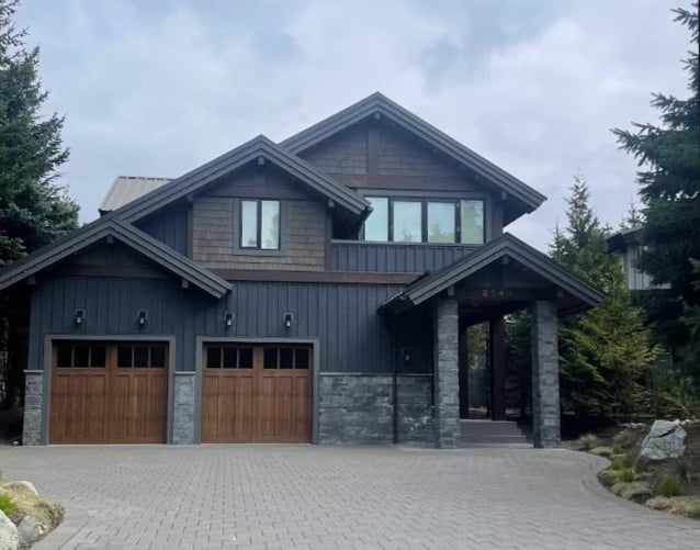 Wood garage doors on an exterior with dark gray stone and siding.