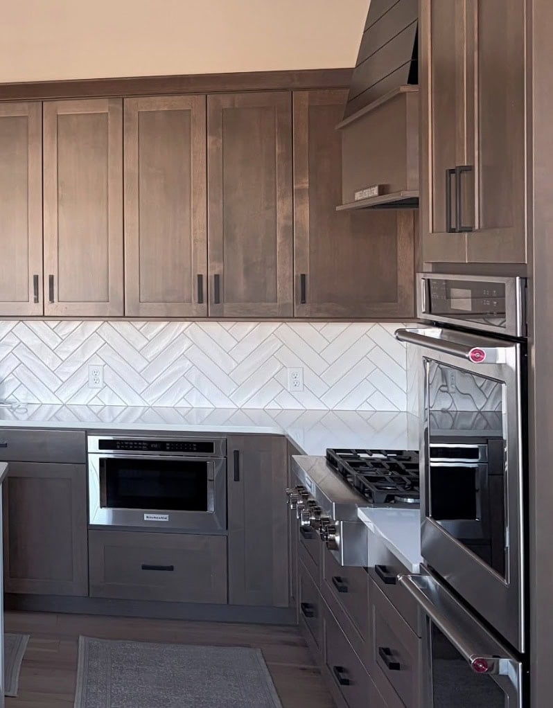 Sherwin Williams Drift of Mist in North east exposure with herringbone subway tile backsplash, white quartz, wood floor, black hardware