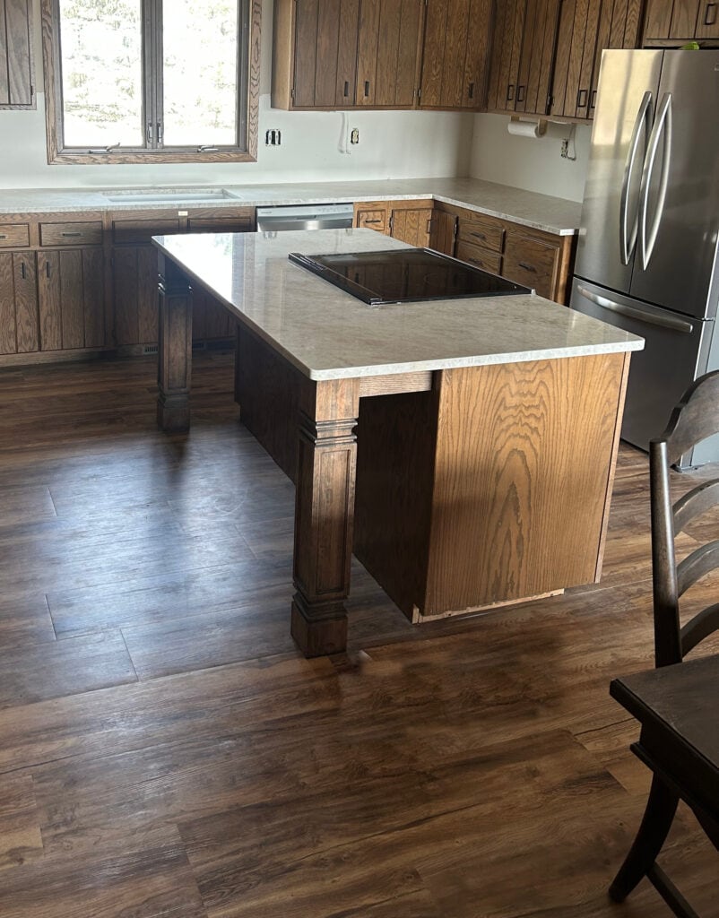 Taj Mahal quartzite countertop update in 1980s or 70s kitchen with dark wood cabinets