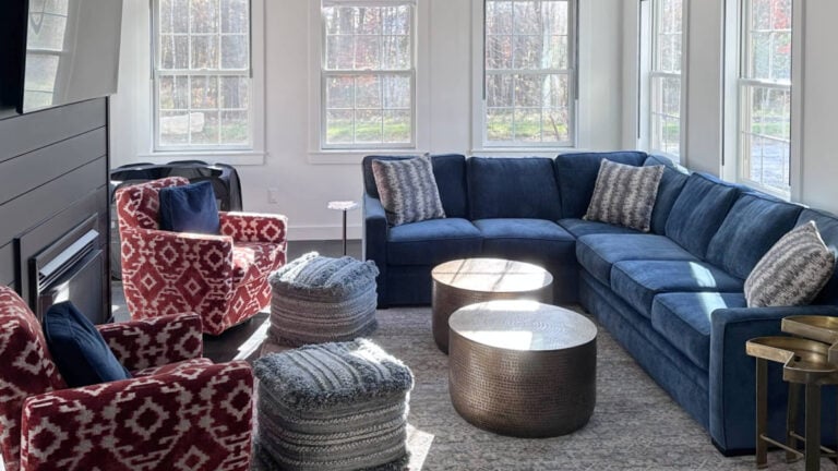 Benjamin Moore Super White in bright living room wiht blue sectional and red patterned accent chairs, black fireplace